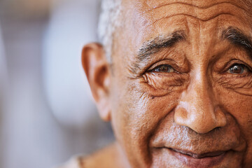 Portrait of a happy, kind black senior mans face with wrinkles, smile and friendly in a retirement home. Happiness, joy and positive elderly black man smiling and feeling content with retired life