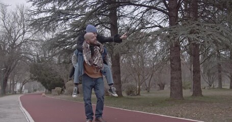 Joyful couple shares a loving piggyback ride along a scenic park path. - Powered by Adobe