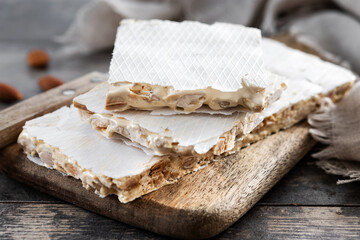 Traditional Christmas sweet, pieces of delicious almond nougat on wooden table