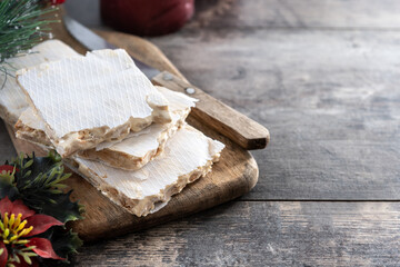 Traditional Christmas sweet, pieces of delicious almond nougat on wooden table. Copy space