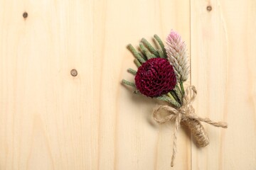 Stylish boutonniere with flowers on wooden table, top view. Space for text