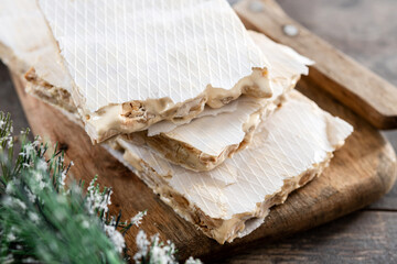 Traditional Christmas sweet, pieces of delicious almond nougat on wooden table