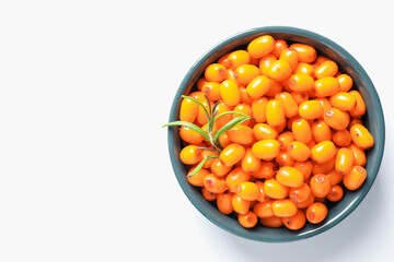 Ripe sea buckthorn berries and leaves in bowl on white background, top view. Space for text
