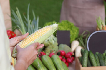 Woman choosing fresh vegetables from stall at farmer's market, closeup