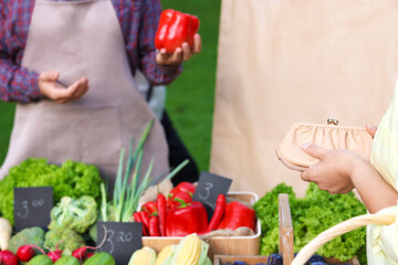 Woman choosing fresh vegetables from stall at farmer's market, closeup