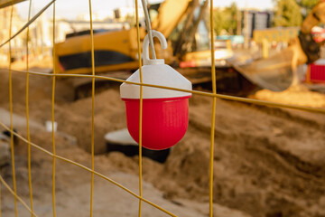 Red signal lantern on mesh fence around construction site.