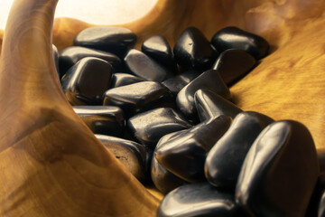 Wooden bowl filled with black shungite stones.