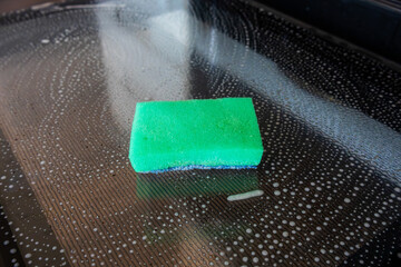 Green sponge on soaped glass surface