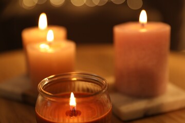 Burning candles on table against blurred lights, closeup