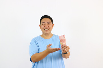 Young asian guy holding money and pointing up finger