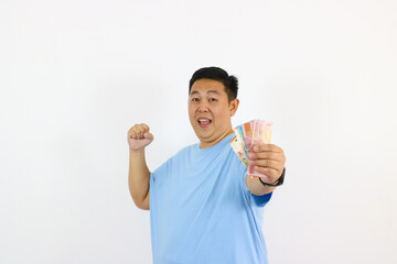 Young asian guy pointing finger up to money and smiling