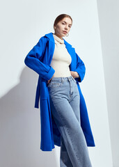 a beautiful woman in a long blue coat on a light background