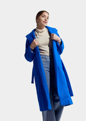 a beautiful woman in a long blue coat on a light background