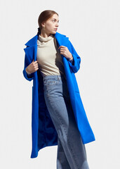 a beautiful woman in a long blue coat on a light background