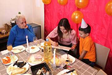 People having fun drawing on a blackboard while sitting at a festive table. Soft lighting.