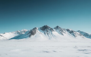 Panoramic view of snow-covered mountain peaks against a pristine blue sky, showcasing the serene beauty and grandeur of a winter landscape