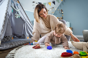 Naklejka premium Mother and child playing together with children's toys in the children's room