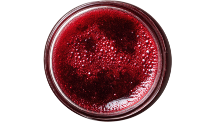 Overhead view of a glass vessel filled with a deep red, bubbly liquid against a black backdrop
