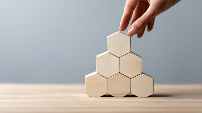 Main pla&ccedil;ant des blocs hexagonaux en bois pour former une pyramide