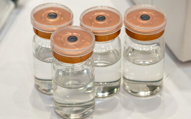 Medical vials, containing a liquid substance such as a vaccine and medication. These vials are typically used to store and administer injectable drugs or biological products.