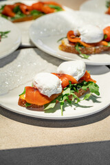 Healthy open sandwich with poached eggs, arugula and smoked salmon served on multigrain bread