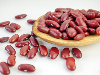 Red bean seeds on a wooden spoon on a white background