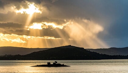 Dramatic sunset over a lake, sunbeams piercing clouds