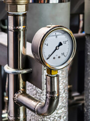 Pressure gauge mounted on industrial piping in a factory setting