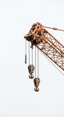 Close up of a large industrial crane boom and hooks against a white sky