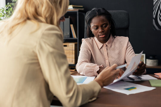 Diverse women collaborating on business data in office