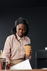 African american businesswoman holding coffee cup reading documents