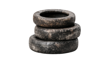 Stacked, used vehicle tires, with weathered appearance, against a stark black background