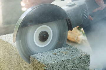 Worker cutting cinder block with angle grinder