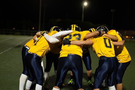 American football team huddling discussing strategy at night