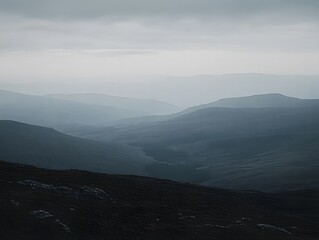 Misty mountain range landscape with hills and cloudy sky in layered vista