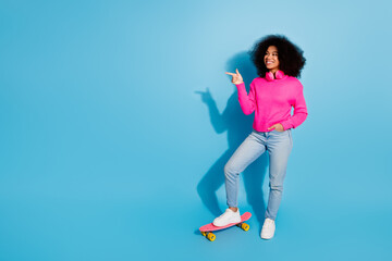 Cheerful young woman in pink sweater posing with a playful gesture against a vibrant blue background
