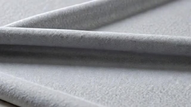 A close up of two gray cylindrical objects lying on a gray textured surface view
