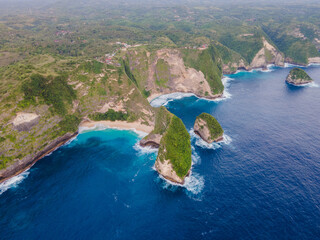 Aerial rocky beach island with turquoise ocean waves at Kelingking Beach, Nusa Penida. Perfect tropical travel and adventure