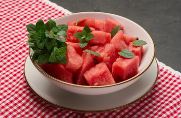 Plate full of diced watermelon garnished with fresh mint. Top view