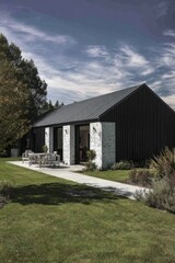 Obraz premium Modern house showcasing sleek architecture and natural surroundings, featuring a well-maintained lawn and cozy outdoor seating area under a clear blue sky
