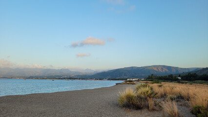 A serene golden hour view from the Laghetti di Marinello Nature Reserve across the Gulf of Patti in Sicily, Italy.