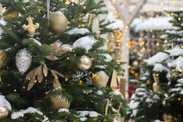 Christmas tree with snow on the branches at the city fair, winter wood filled with festive garlands...