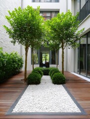 Obraz premium Interior courtyard with trees, shrubbery, gravel path, wooden deck, and modern building