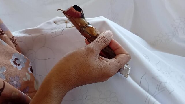 hand holding a canting to batik cloth