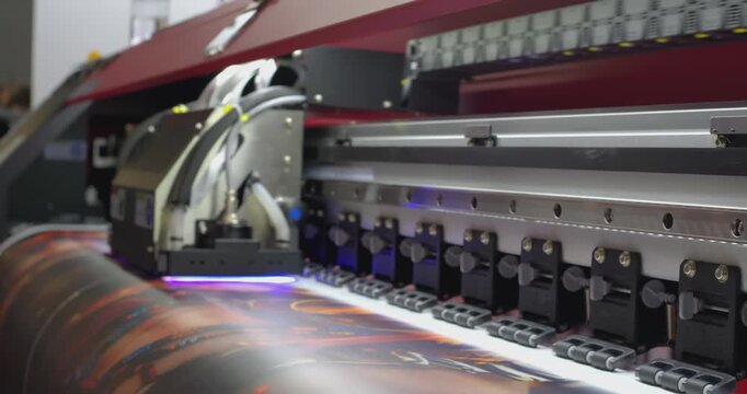 Large format printer printing a colorful image on white vinyl