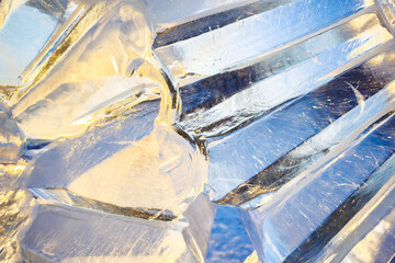 An intricate ice sculpture reflects sunlight in snowy landscape, blend of clear and frosted surfaces. Striking patterns and textures of the ice. Winter season festival art, nature beauty.