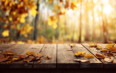 Wooden table with fallen leaves in foreground, soft focus of autumn foliage and sunlight