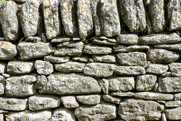 A detailed close-up view of a rustic stone wall in France, showing the textures and patterns of the stacked rocks
