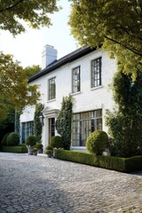 Beautiful white house with manicured garden and cobblestone driveway in a peaceful suburban neighborhood during the golden hour of late afternoon