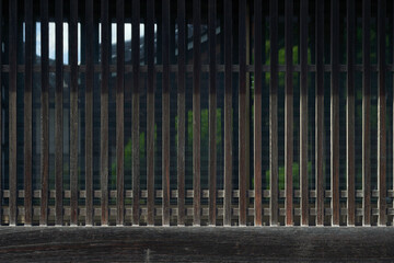 Fototapeta premium 格子の目隠し越しに見える建物と植物。伝統的な日本建築の背景用素材